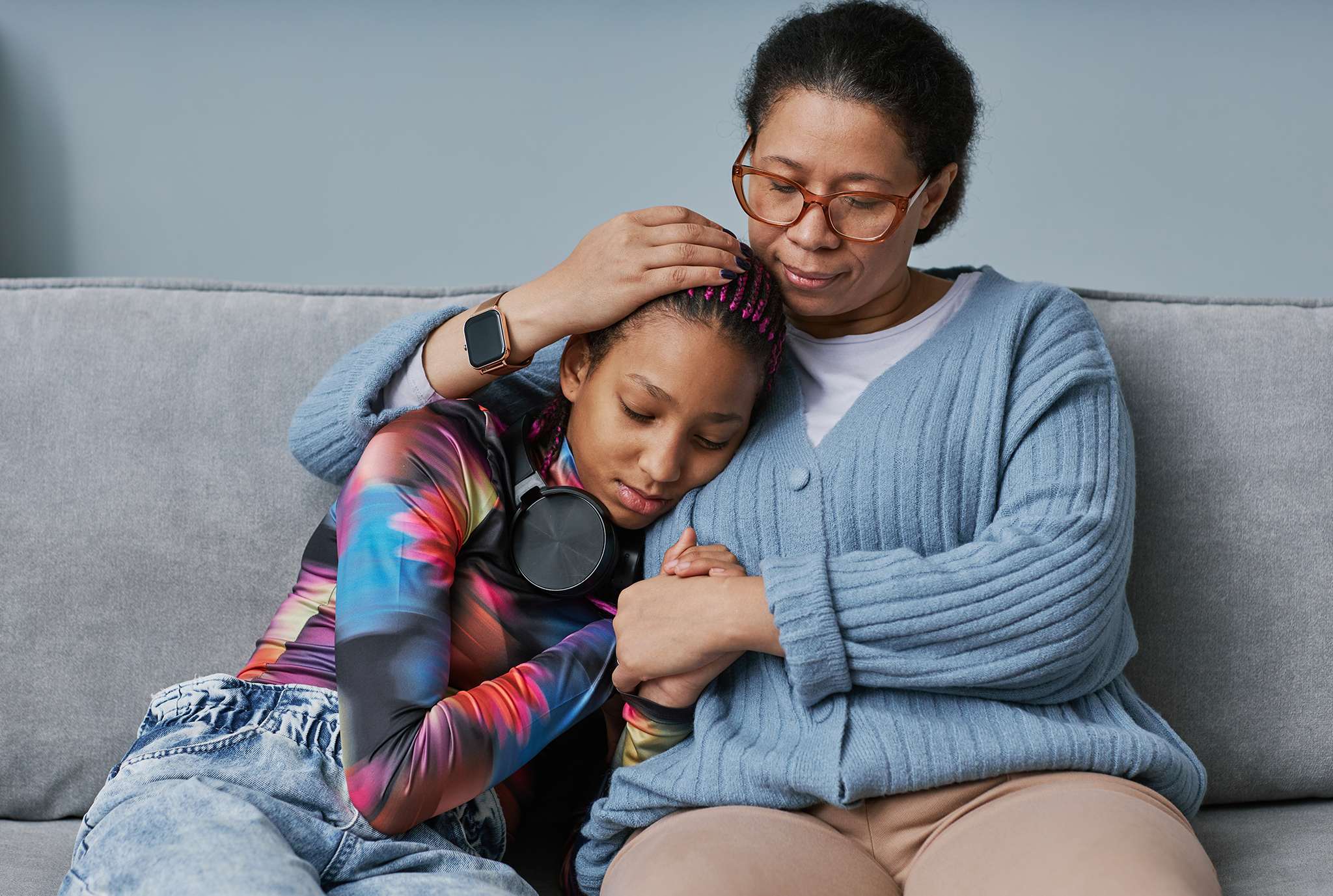 A woman and a young girl are seated together on a cozy couch, sharing a moment of connection and warmth.