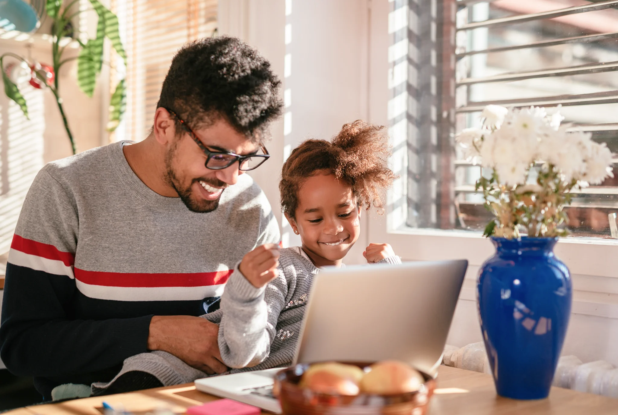 Niños pequeños aprendiendo en una computadora portátil o tableta con un padre cerca ayudando con una lección en línea.