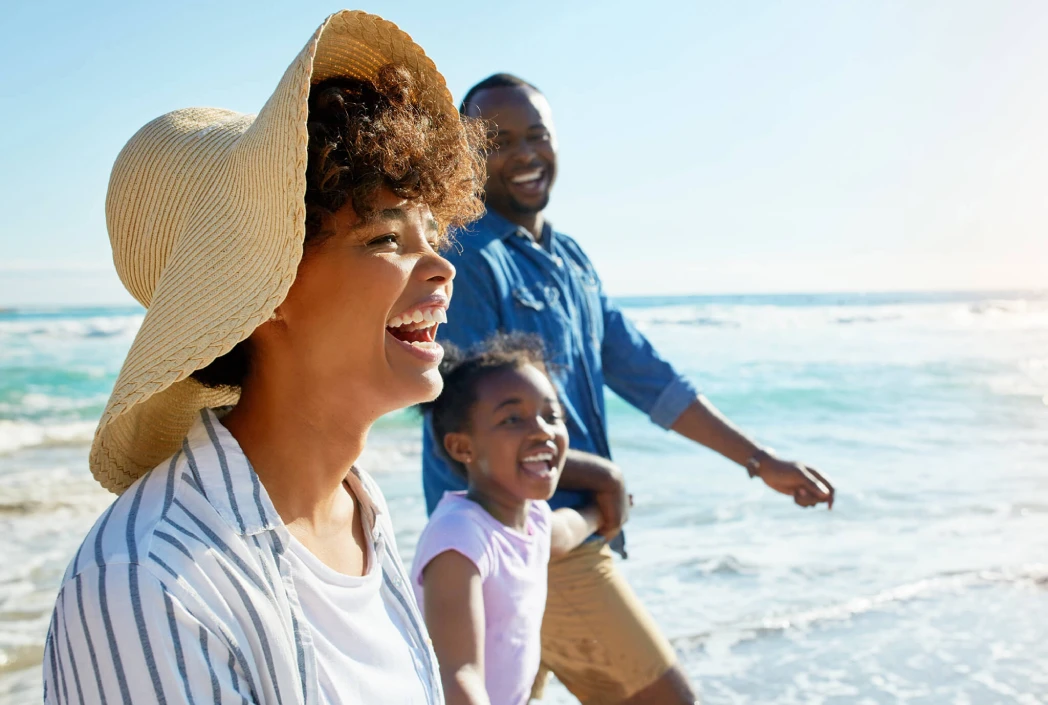 Happy family walking along the beach together, enjoying a summer vacation by the ocean