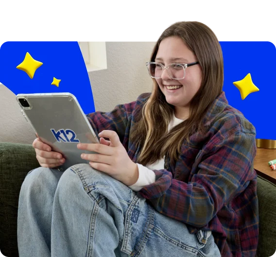 Person seated on a couch using a K12-branded tablet. Decorative blue graphic shapes and yellow star illustrations appear in the background.