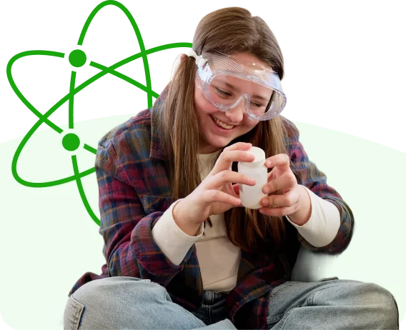 Learner wearing safety goggles while conducting a hands-on science activity, holding a small container. A green atom graphic appears in the background.