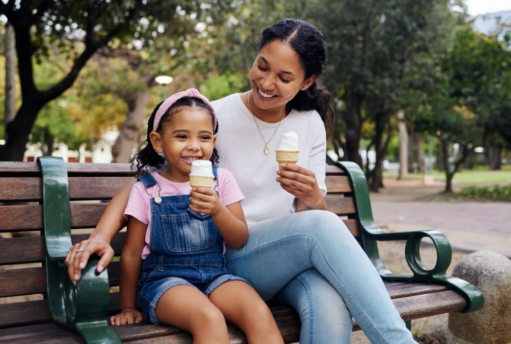 Adult and child enjoying ice cream together outdoors, illustrating quality time and after-school family traditions.
