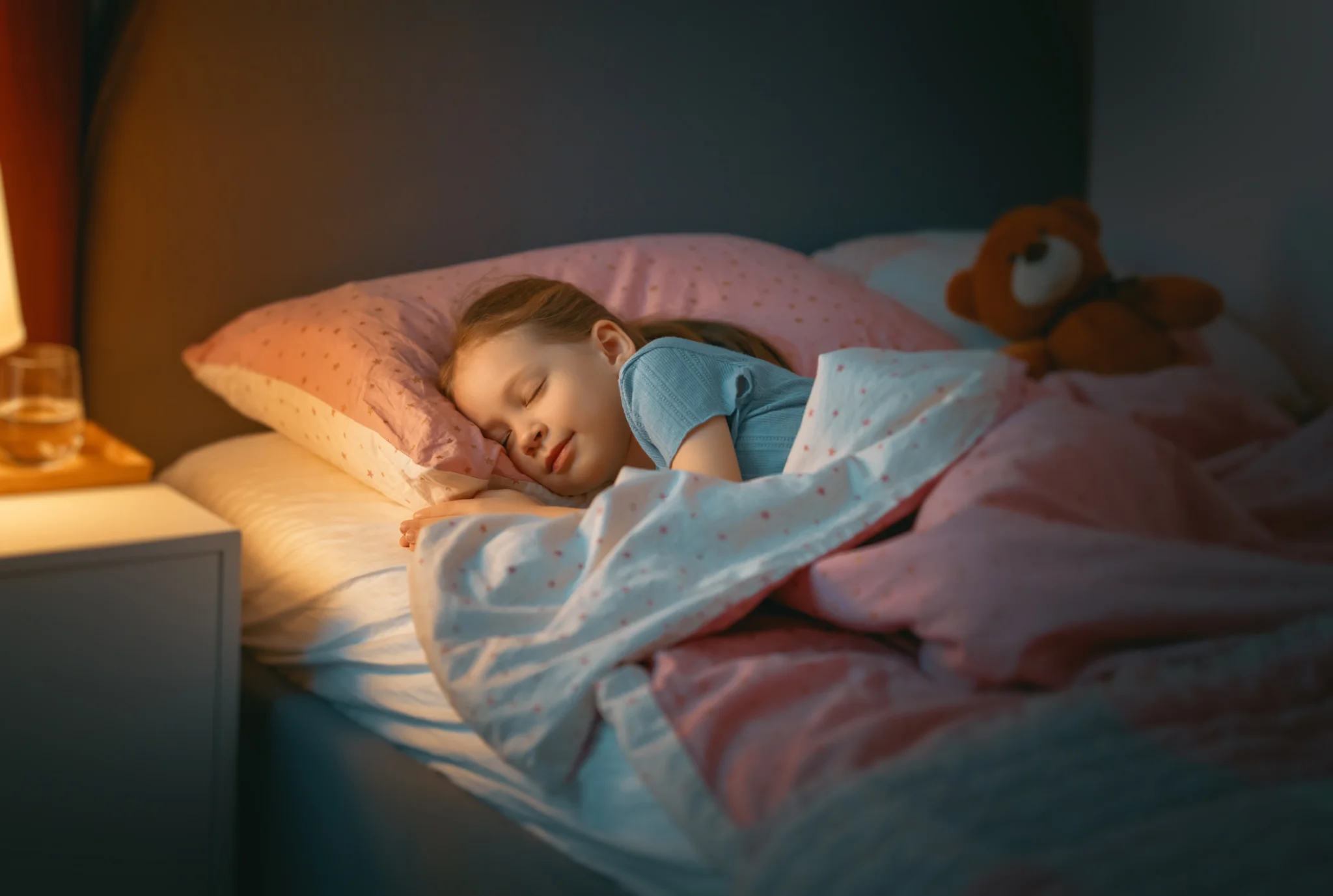 Child resting comfortably in bed, illustrating the importance of healthy sleep habits during the school year.