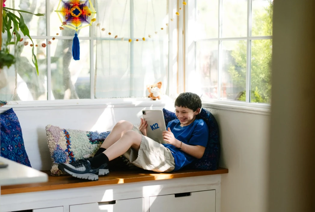 Learner engaging with educational content on a K12 tablet, demonstrating flexible online learning in a comfortable home environment.