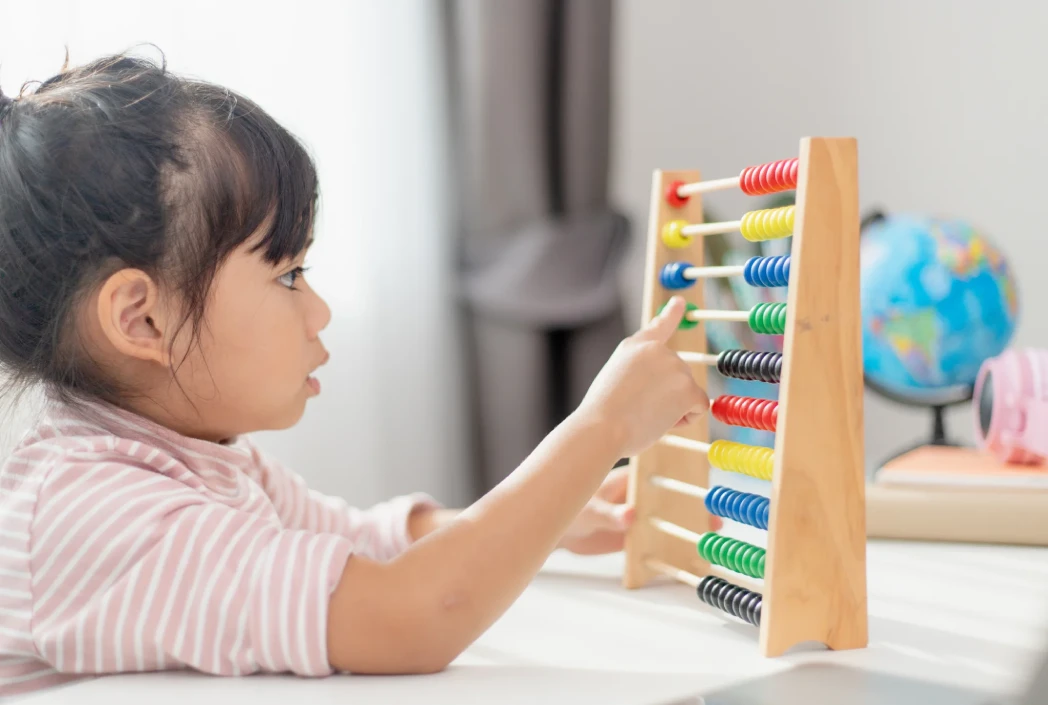 Young learner practicing counting and number recognition with an abacus, supporting foundational math skills.
