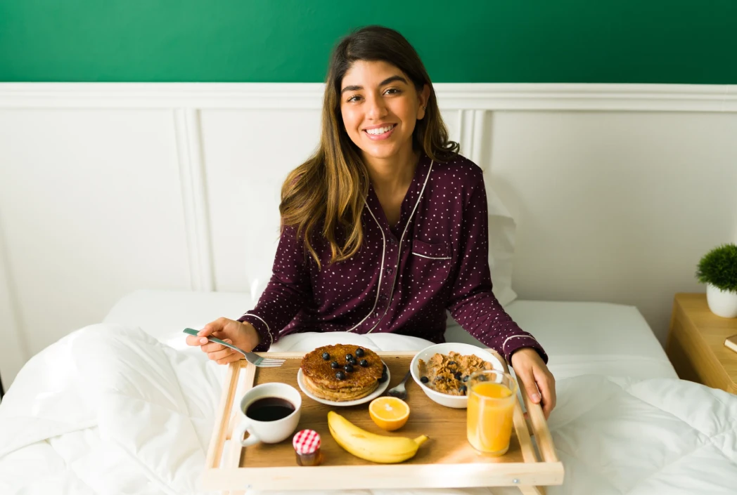 Person enjoying a healthy breakfast in bed, representing self-care, wellness, and a positive start to the day.