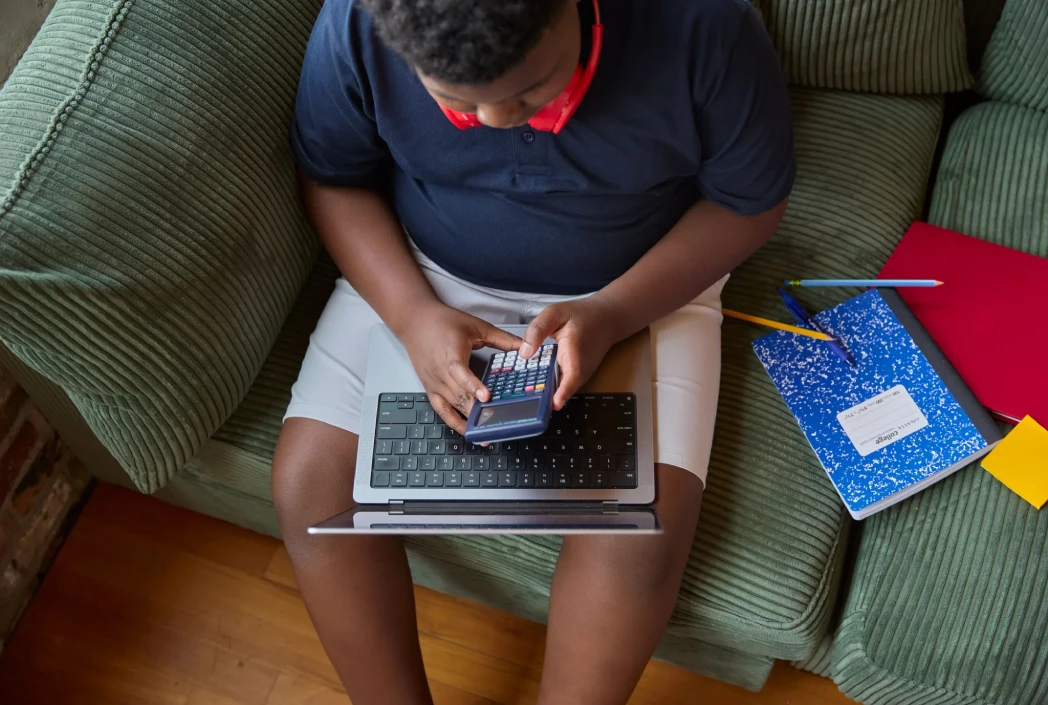 Student working on math assignments with a calculator and laptop, demonstrating organization and academic preparation for the school year.