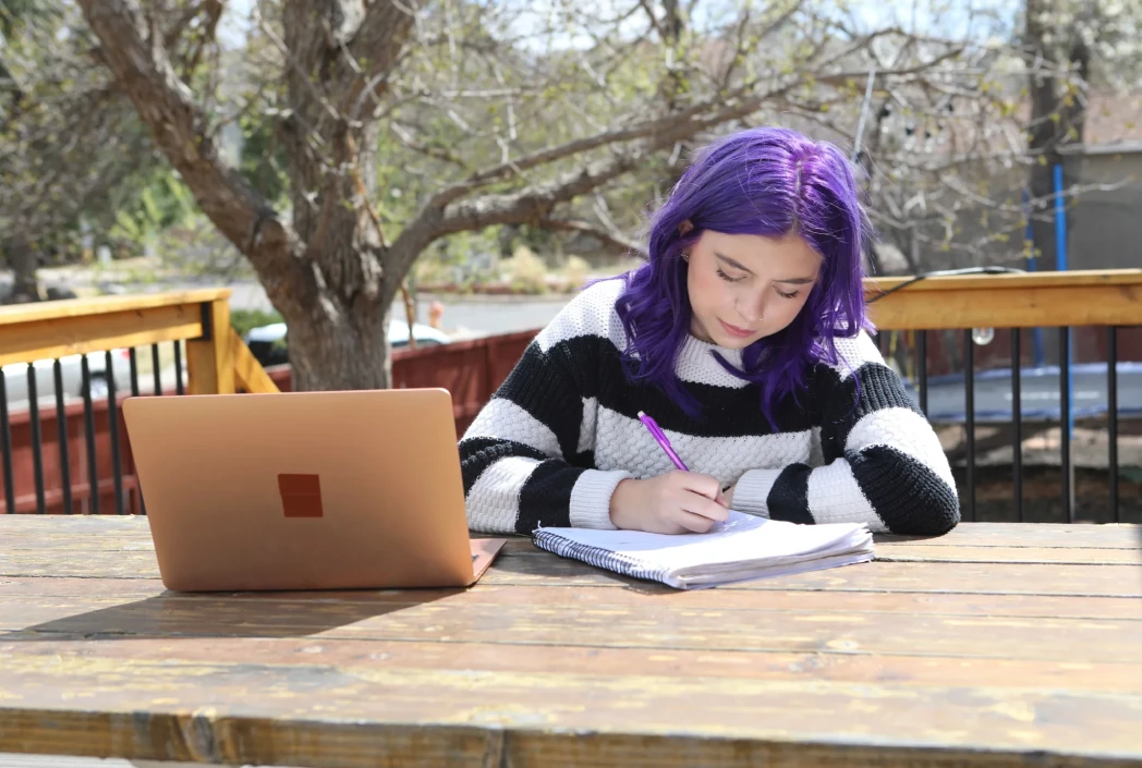 Learner completing writing and reflection activities outdoors, demonstrating the flexibility to learn and study from any location.