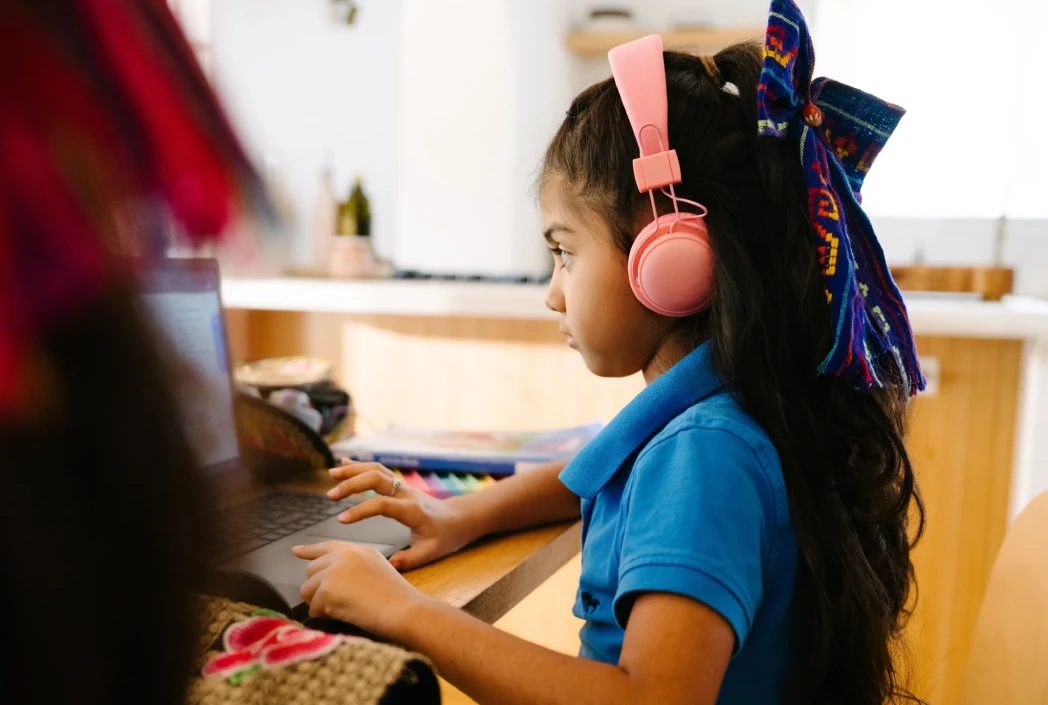 Student uses headphones while attending an online lesson, creating a focused learning environment that supports concentration and academic achievement.