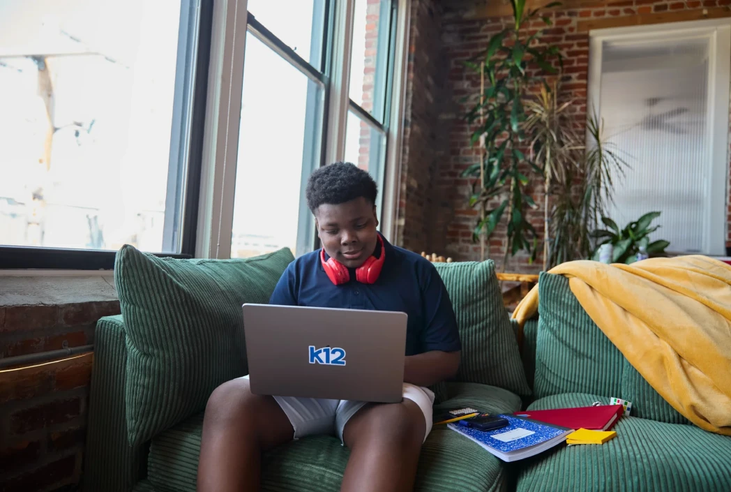 Student learns from home on a K12-powered laptop, demonstrating the flexibility and personalized support of online education.