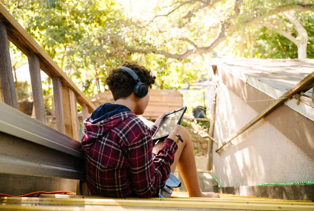 Student using a tablet outdoors to practice reading comprehension skills through digital learning and interactive reading activities.